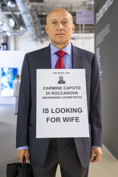 Carmine Caputo di Roccanova mit seinem Schild IS LOOKING FOR WIFE an der Art Basel am 15. Juni 2022. © KEYSTONE/Georgios Kefalas