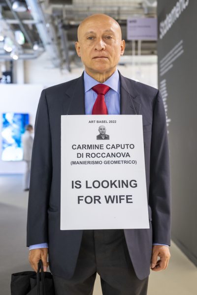 Carmine Caputo di Roccanova mit seinem Schild IS LOOKING FOR WIFE an der Art Basel, am 15. Juni 2022. © KEYSTONE/Georgios Kefalas